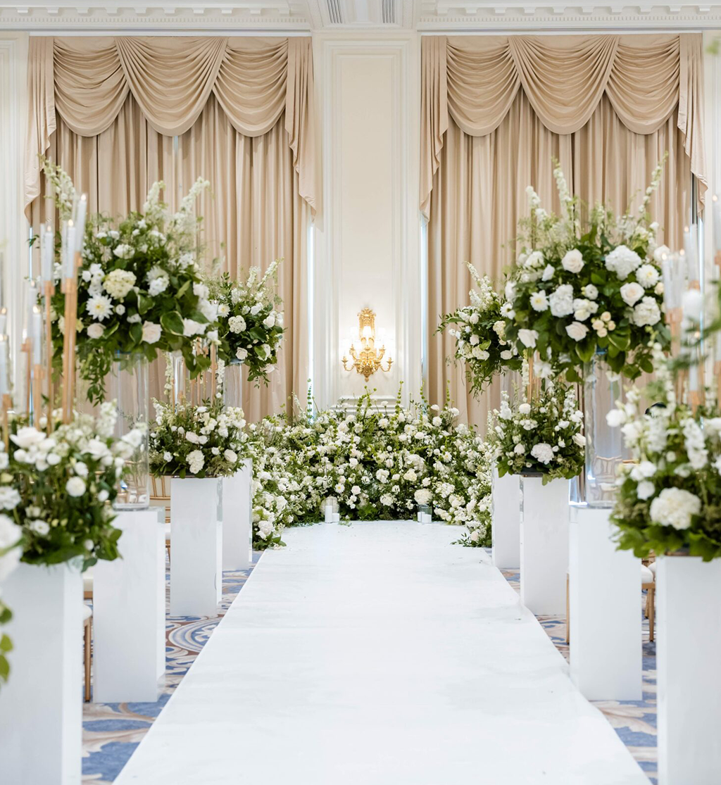 Luxury wedding ceremony aisle styling with white floral installations and candle plinths by Muse Styling Scotland