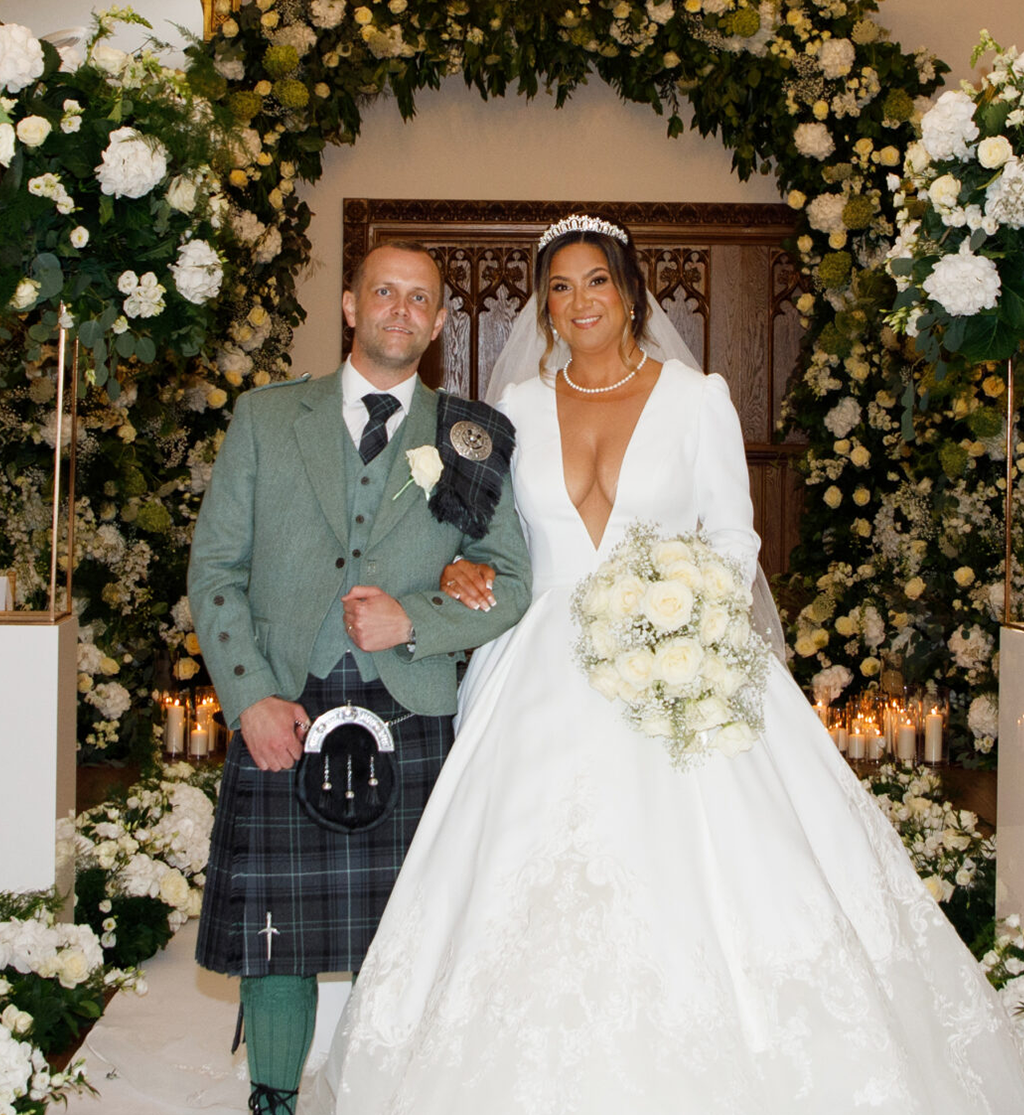 Bride and groom at Crossbasket Castle ceremony with luxury floral aisle styling by Muse Styling