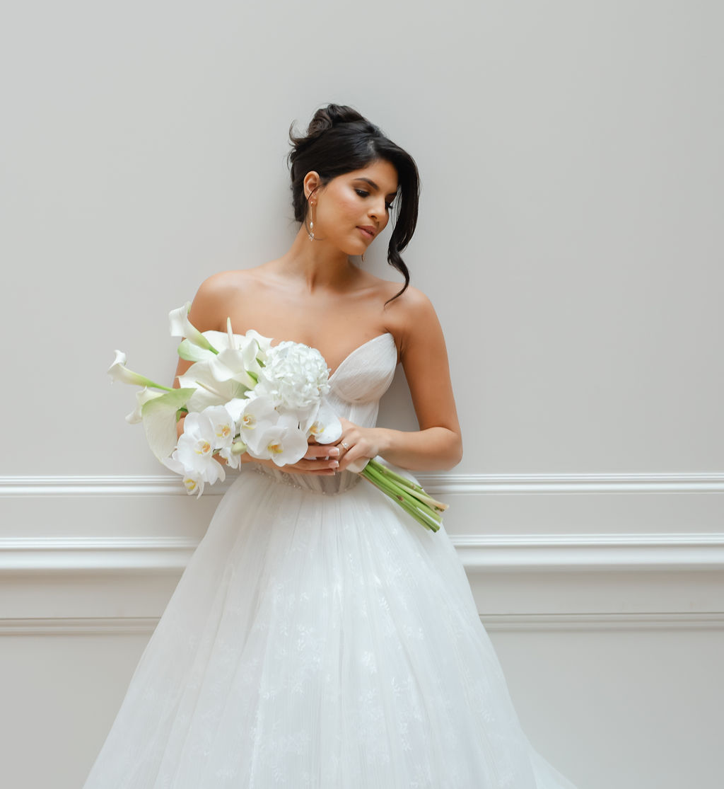 Bride wearing strapless wedding gown holding modern white bouquet during luxury wedding photoshoot at Collector’s Hall with Opus Couture