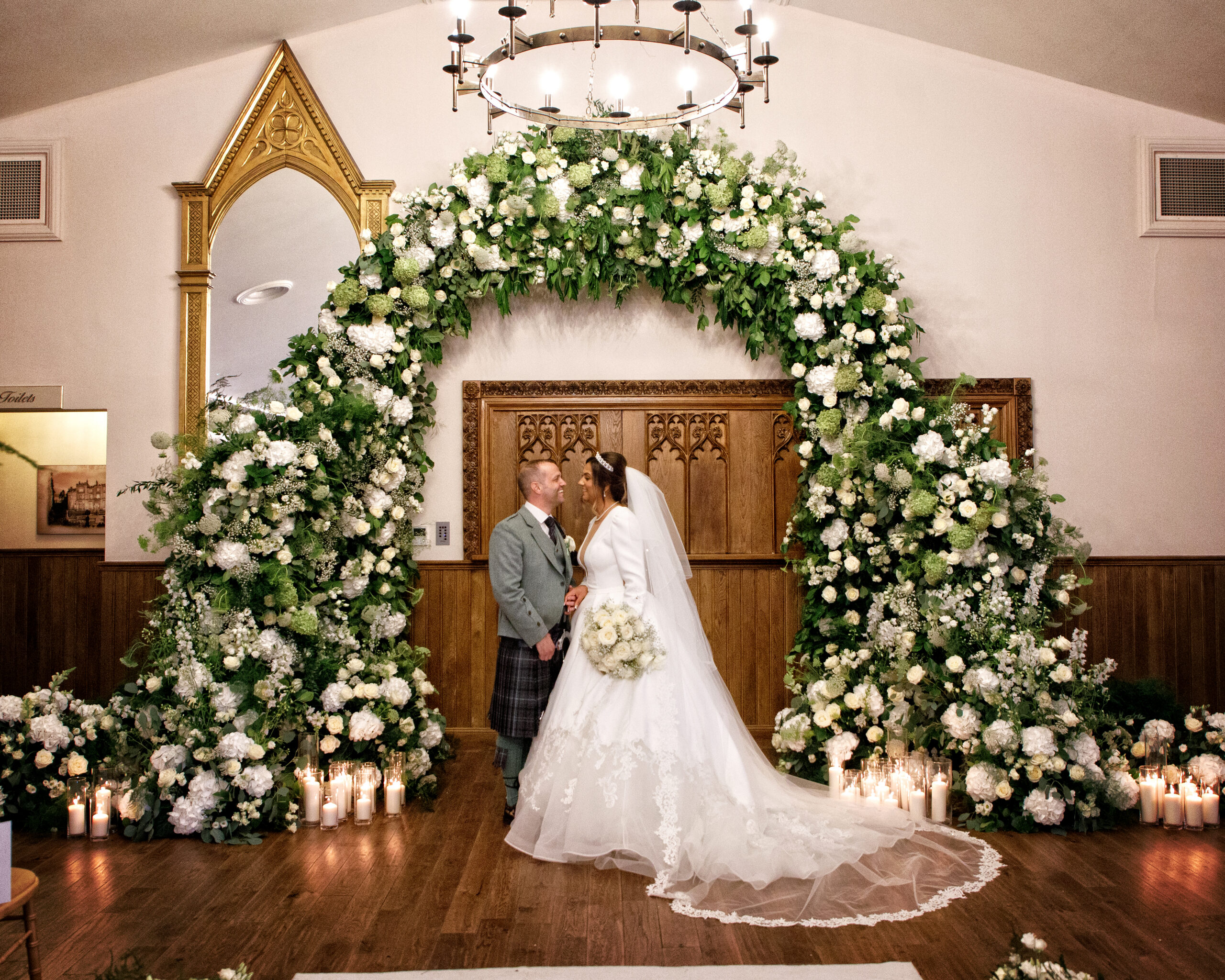 Bride and groom under floral arch at Crossbasket Castle wedding styled by Muse Styling Scotland