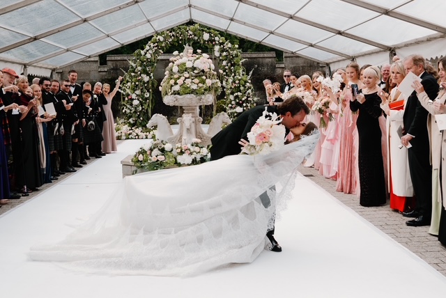 Bride and groom beneath a romantic floral ceremony arch at Dundas Castle during their luxury destination wedding in Scotland.
